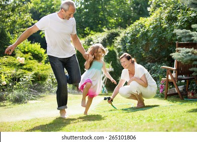 Mädchen und Großeltern, die im Garten spielen und Wassersport betreiben
