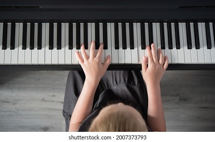 a girl in a gray dress plays an electronic piano. Home schooling. Top view image - Powered by Shutterstock