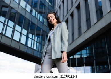 Girl In Gray Suit With Headphones Listening To Music Going Home From Buisness Center After Successful Conference And Video Call With Colleaugues.