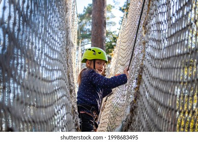 a girl in a green helmet runs the distance in the forest extreme rope park passing through the protective net - Powered by Shutterstock