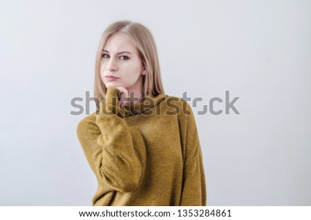 Girl in a green sweater posing on white background. interested, at a loss.