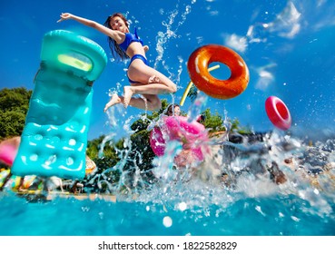 Mädchen in einer Jugendgruppe haben Spaß im Schwimmbad, tauchen mit aufblasbaren Spielspielzeug-Donnüssen, Matrassspringen und im Wasser schwimmen.