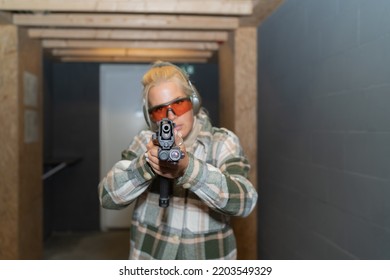 A Girl With A Gun, A Blonde Takes Aim And A Special Pistol With A Laser Sight.  Front View Photo With Soft Focus.