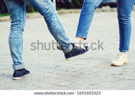 Girl and guy bump feet outdoors. Coronavirus epidemic. Foot shake style of greetings. Coronavirus prevention. Covid 19 prevention. People, lifestyle 2020. Young couple greeting with foot.