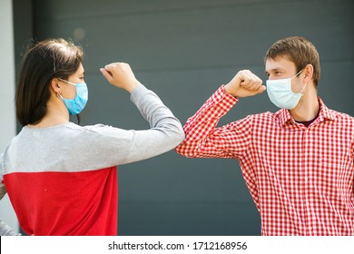 Girl And Guy Greeting With Elbows Outdoors. New Real Life. Coronavirus Quarantine. Coronavirus Epidemic. Friends In Safety Mask Outside. Young Couple Wear Face Masks Outdoors. Social Distancing.