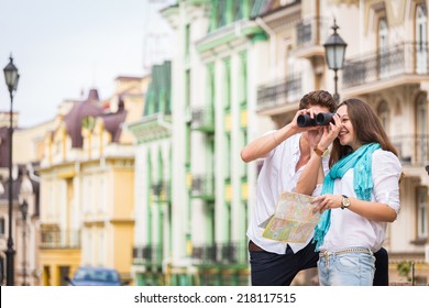 Girl And Guy On The Streets Of European Cities. Couple Walking Along The Picturesque Street. They Look At The Sights. Travel, Couple, City, Map, Beauty, Walk - Travel Concept. Article About Travel