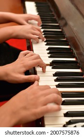 A Girl And A Guy Play The Piano In Four Hands. Rehearsal And Training At A Music School.