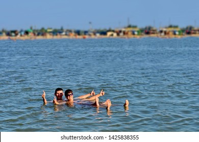 The Girl And The Guy Swims In The Dead Sea And Smile. Rest On The Sea. Family Vacation At Sea. Bathing In Salt Water.