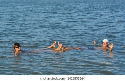 The Girl And The Guy Swims In The Dead Sea And Smile. Rest On The Sea. Family Vacation At Sea. Bathing In Salt Water.