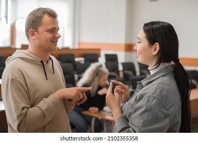 The Girl And The Guy Talk In Sign Language. Two Deaf Students Chatting In A University Class.