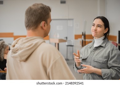 The Girl And The Guy Talk In Sign Language. Two Deaf Students Chatting In A University Class.