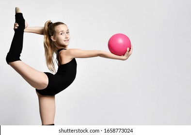 girl gymnast in black body and leggings is training with a pink gymnastic ball. children's professional sport. Rhythmic gymnastics.