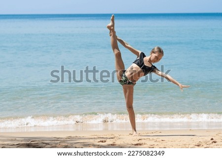 girl gymnast doing splits on the beach	
