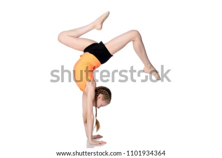 The girl gymnast performs a handstand with bent legs.The concept of childhood, sport, a healthy lifestyle, physical development of personality. Isolated on white background.