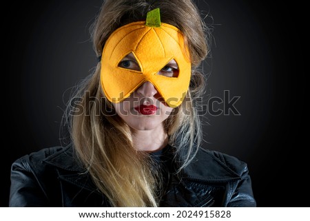  Girl  in halloween mask, dressed in black in pumkin mask, 
with a mystical look isolated over black background.