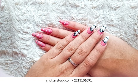 Girl With Halloween Themed Nails On Fluffy White Blanket. Isolated On White Surface. Nails With Ghosts And Eyes