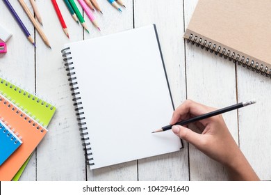 Girl Hand Drawing, Blank Paper And Colorful Pencils On White Wooden Table