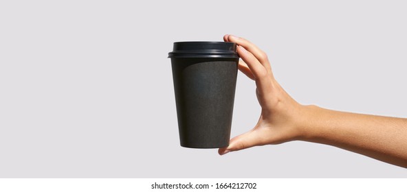 Girl Hand Hold Coffee Plastic Cup. Grey Background With Copyspace. Female Arm Holding Paper Glass. To Go, Away. No Ecology. Without Shadows. Horizontal Banner