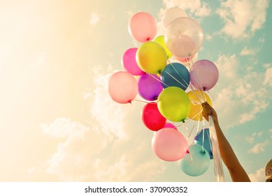 Girl hand holding colorful balloons. happy birthday party. vintage filter effect