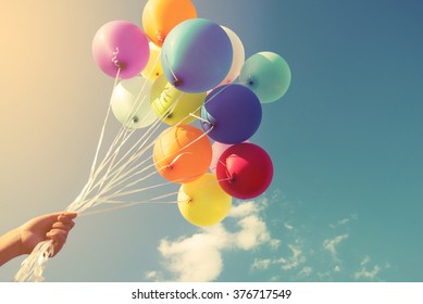 Girl hand holding multicolor balloons done with a retro instagram filter effect, concept of happy birth day in summer and wedding honeymoon party (Vintage color tone)