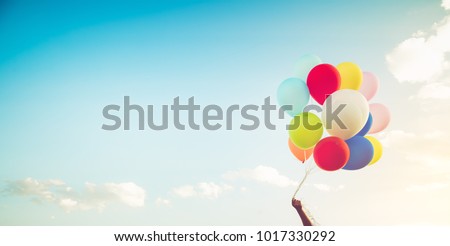 Girl hand holding multicolor balloons done with a retro instagram filter effect, concept of happy birth day in summer and wedding honeymoon party, Vintage color tone style