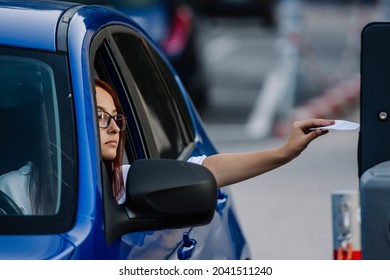 Girl hand inserting the ticket into parking machine to pay. Girl in a car paying inserting the ticket into parking machine.