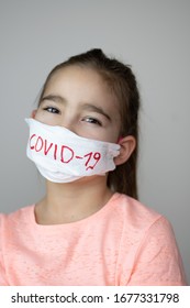 Girl with hand made mask to protect her from Corona virus. COVID-19 written on mask. - Shutterstock ID 1677331798