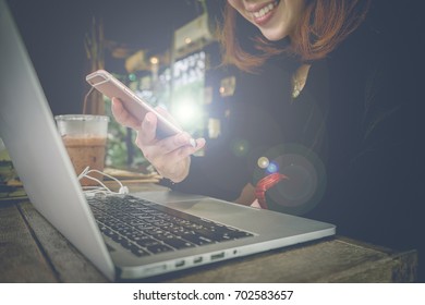 Girl hand using phone with blank screen mobile and laptop computer on wooden desk. - Shutterstock ID 702583657