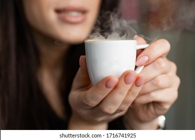 The girl hands holding hot cup of coffee or tea. Hot coffee in the hands close-up - Shutterstock ID 1716741925
