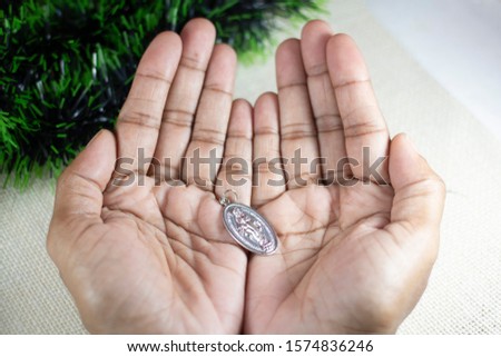 Girl Hands Holding Miraculous Medal and Praying to Our Lady Holy Mary, Mother of God.