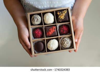 Girl Hands Holds A Box Of Chocolates. Assorted Chocolates Confectionery In Their Gift Box On The White Background