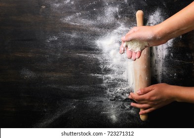 Girl hands keep rolling pin with flour on dark black table, baking background, top view, copy space for your text, meru, recipe. Banner - Shutterstock ID 723271312