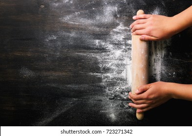 Girl hands keep rolling pin with flour on dark black table, baking background, top view, copy space for your text, meru, recipe. Banner - Shutterstock ID 723271342
