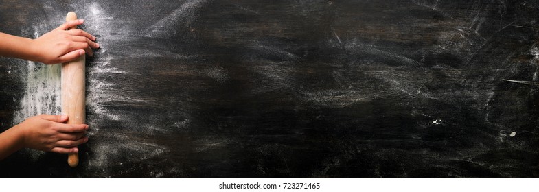Girl hands keep rolling pin with flour on dark black table, baking background, top view, copy space for your text, meru, recipe. Banner - Powered by Shutterstock