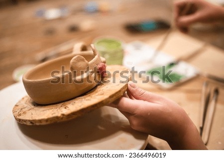 girl hands, pottery studio and painting cup in workshop for makes a creative mug in the form of a frog. Painter, ceramics product and brush process, artistic pattern or production in small business