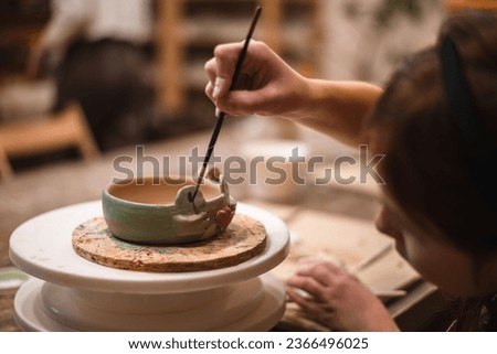girl hands, pottery studio and painting cup in workshop for makes a creative mug in the form of a frog. Painter, ceramics product and brush process, artistic pattern or production in small business