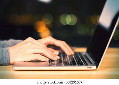 Girl Hands Typing On Laptop On Wooden Table At Night, Close Up