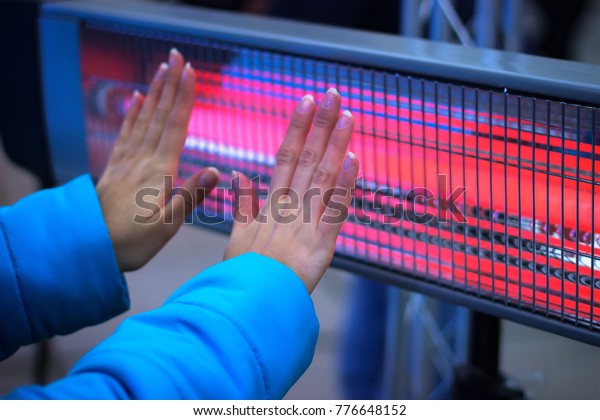 Girl Hands Warming With Heating Radiator at\
evening winter outdoor