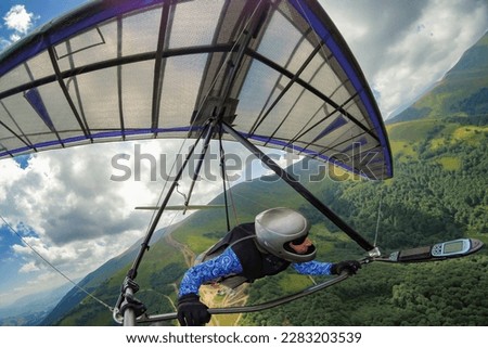 Girl hang glider pilot soars in the mountains on her light kite wing.