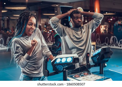 The girl is happy that she defeated the man in the video game. A man grabbed his head because he lost in a video game to a woman in an entertainment center. 