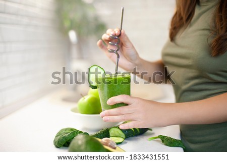 girl has prepared and holds in a glass of detox a smoothie drink made from a green apple, cucumber and spinach. Morning detox for a healthy lifestyle, weight loss, ketone diet, raw food diet