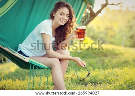 girl has a rest in a hammock with a drink