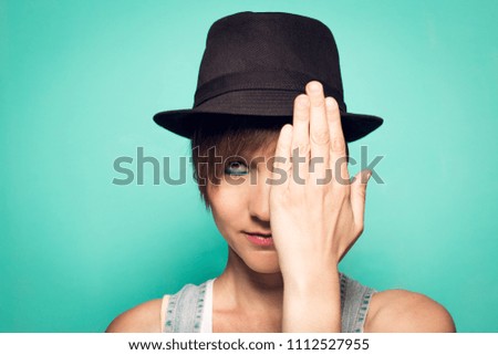 Girl in a hat and covering her eye with her hand.Close-up of a girl in a hat