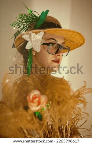 A girl in a hat and glasses with a flower in her hands
