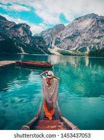 Girl in a hat on the background of the turquoise lake in mountain. Dolomites Alps, lago di Braies, Italy