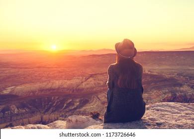 A girl in a hat on top of a hill in silence and loneliness admires a tranquil natural landscape in search of a soul. - Powered by Shutterstock