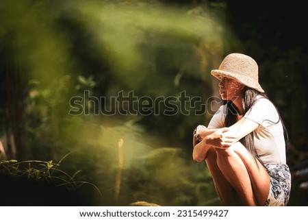 girl with a hat sitting in the forest