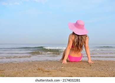 Girl in a hat and swimsuit resting on the beach
