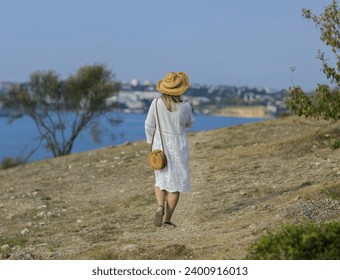 a girl in a hat and white sundress leisurely walks towards the sea Meeting the sea Alone with nature