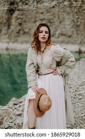 Girl in a hat in a white wedding dress boho near the lake